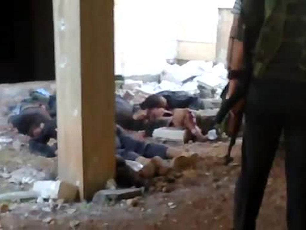 An image grab taken from a video uploaded on YouTube on November 1, 2012 shows rebel fighters standing near alleged bodies of Syrian soldiers