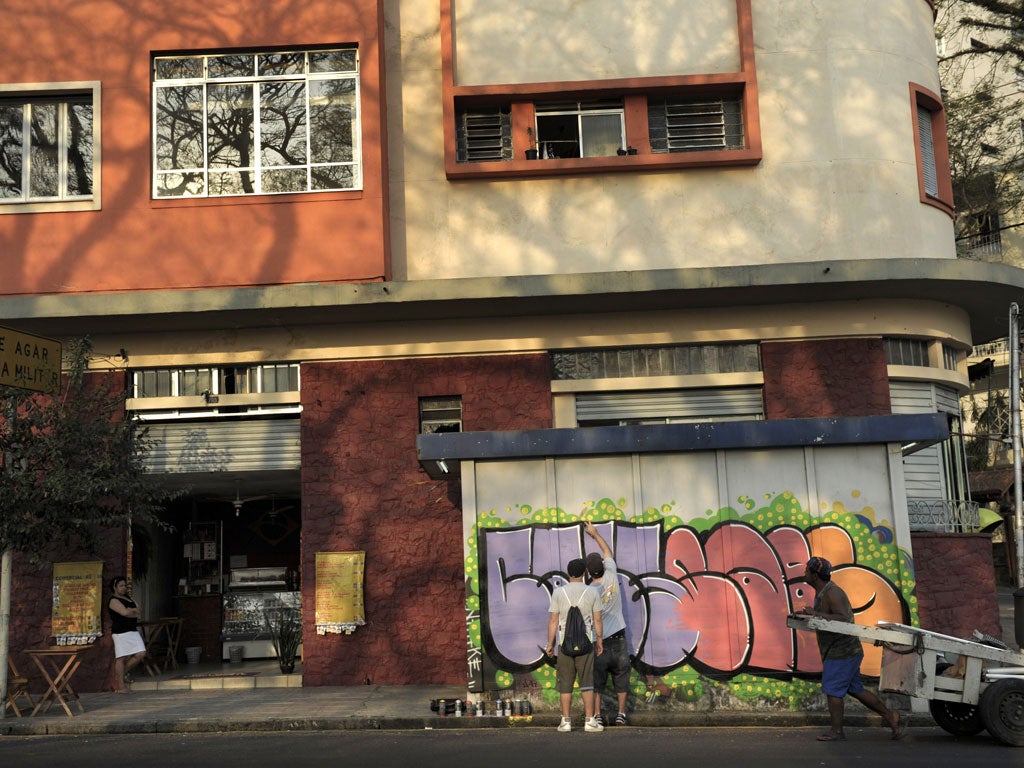 Spray day: Two street artists painting a news stand in Sao Paulo's Paraiso neighbourhood