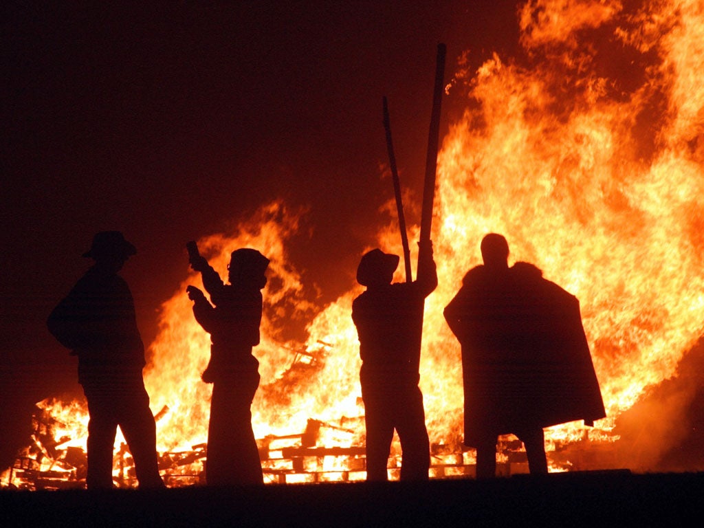 Revellers stand near the fires during the first of the Bonfire Night celebrations on September 25, 2004 in Burgess Hill, England.