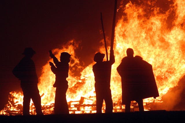 Revellers stand near the fires during the first of the Bonfire Night celebrations on September 25, 2004 in Burgess Hill, England.