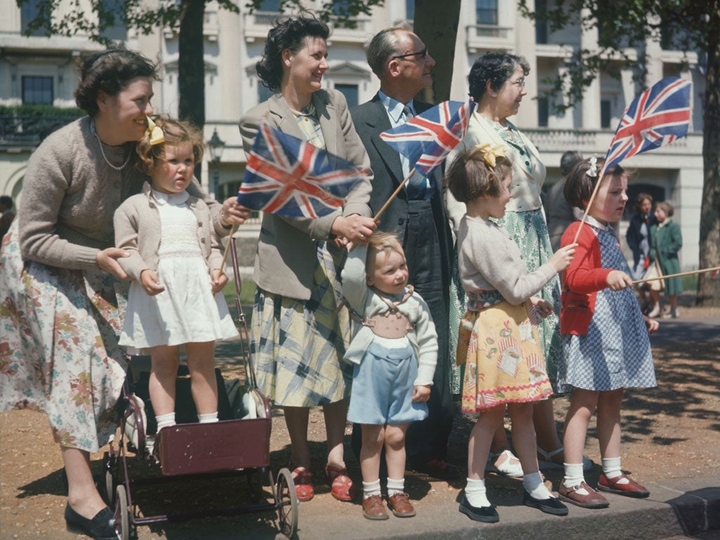 A family celebrating Empire day, waving Union Jack flags in the streets of London, England circa 1950.