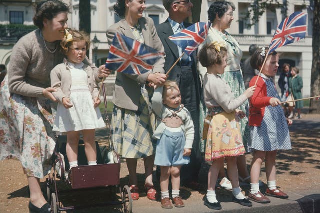 A family celebrating Empire day, waving Union Jack flags in the streets of London, England circa 1950.