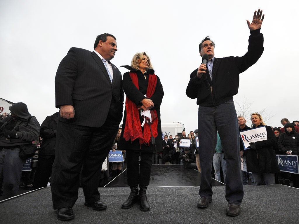 Mitt Romney speaks as his wife Ann Romney (C) and New Jersey Governor Chris Christie (L) look on during a campaign rally in Des Moines, Iowa, on December 30, 2001.