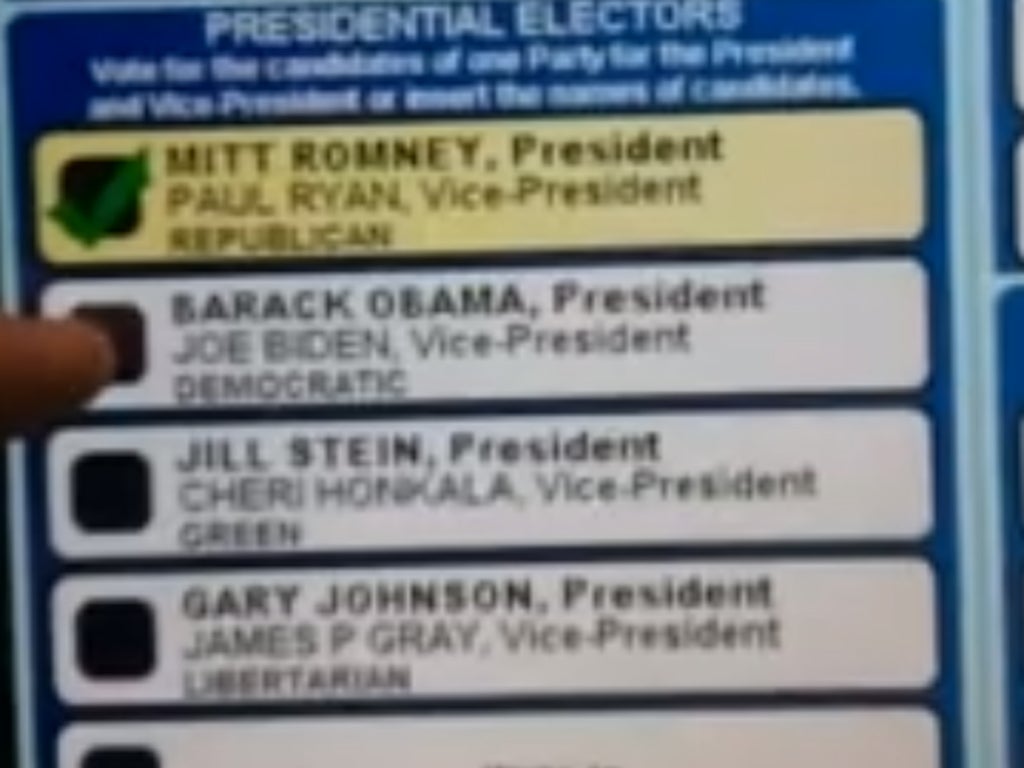 The video appears to show a voter selecting Obama's name on the touchscreen, which then highlights Romney's
