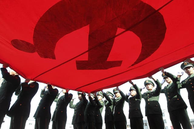 Soldiers in Beijing hold up the Communist Party flag