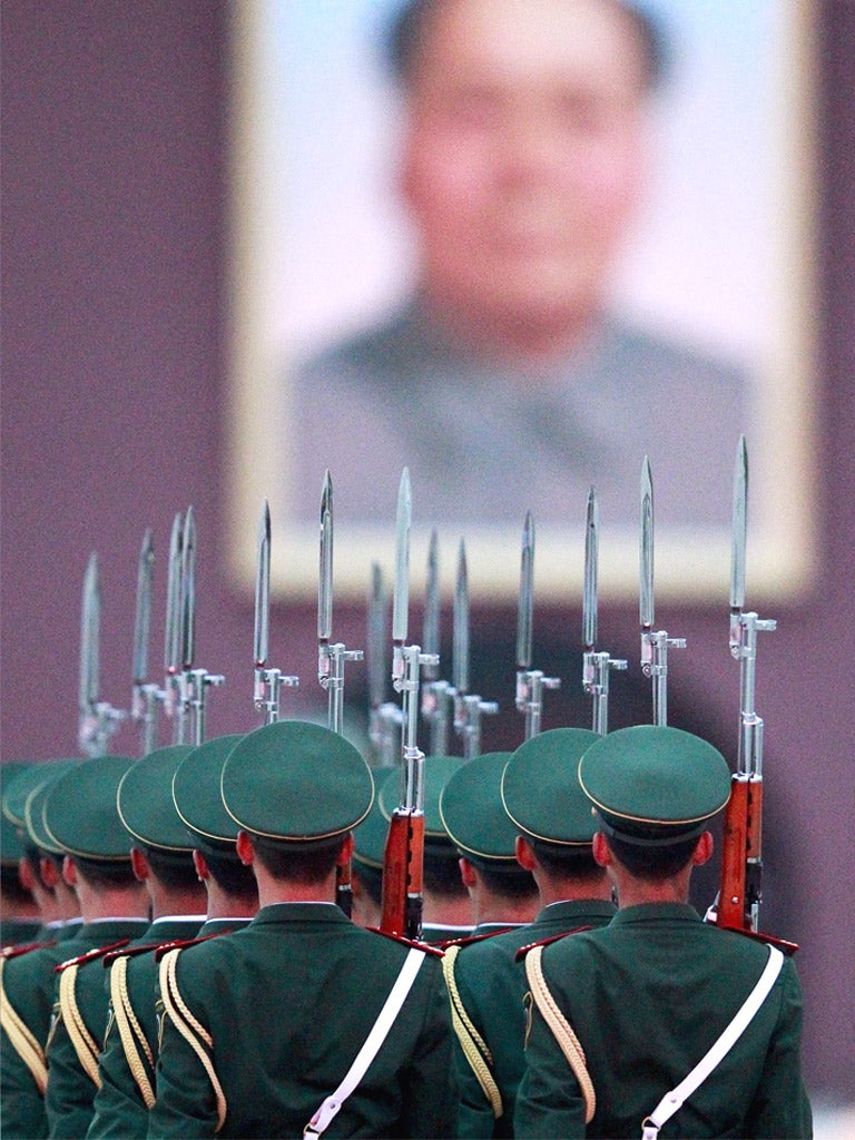 Soldiers march in Beijing below a portrait of Mao Zedong
