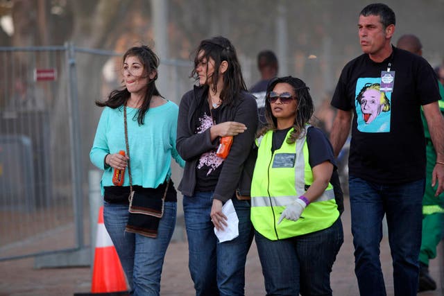 A injured woman, second left, holds her arm as she walks with medical personnel, second right, after she and others were injured during a concert by Linkin Park in Cape Town, South Africa