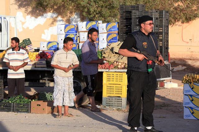 A pro-government Libyan fighter holds his gun as people shop at a market in the city of Bani Walid