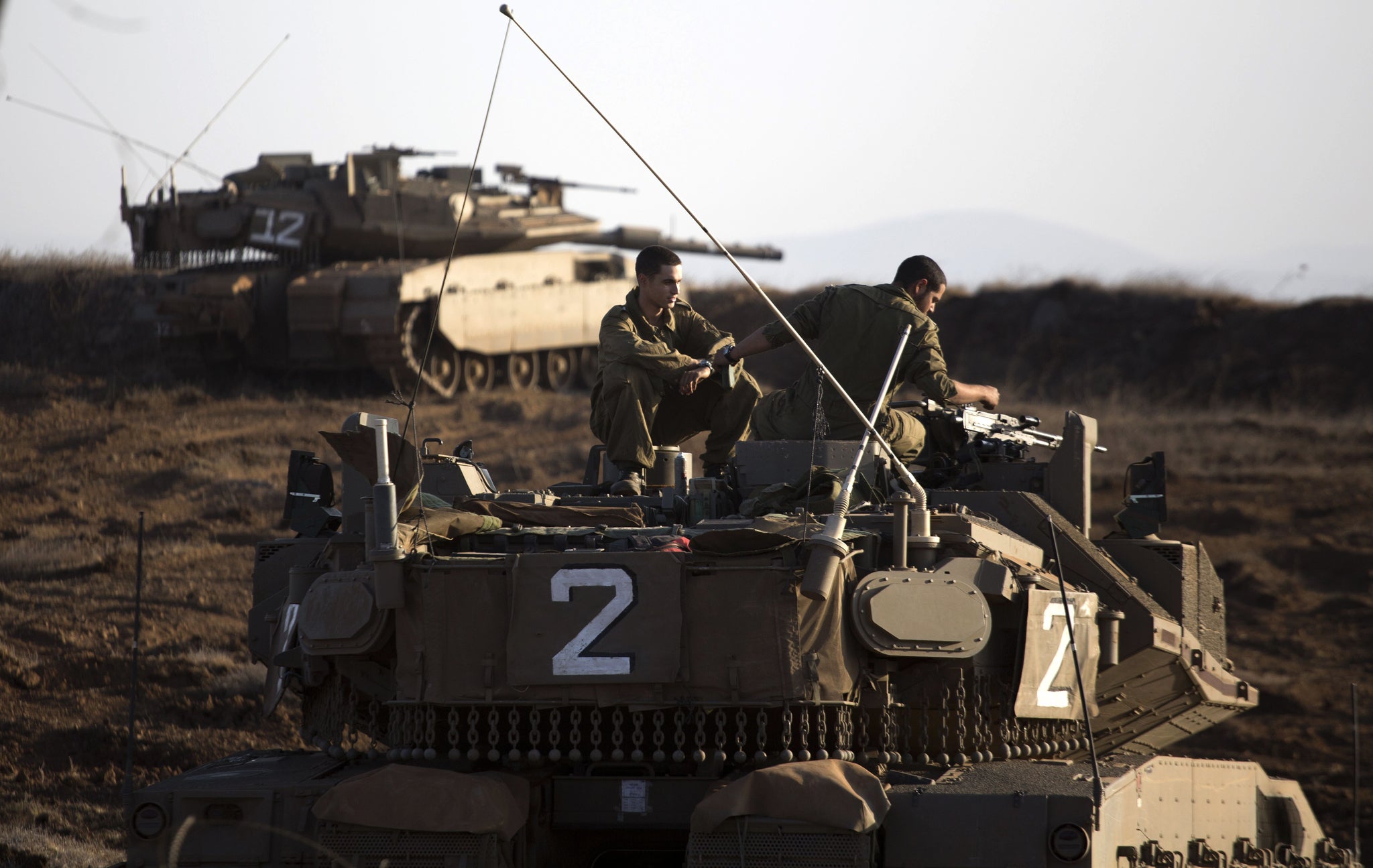 An Israeli Merkava tank crew sit on the Golan Heights overlooking the Syrian village of Breqa on 6 November 2012