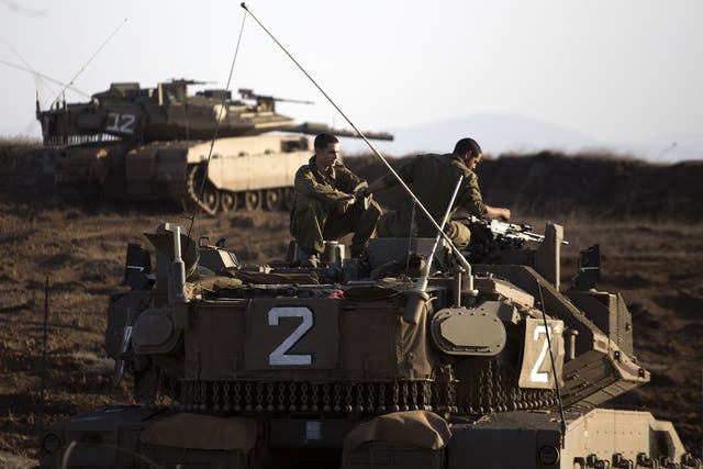 An Israeli Merkava tank crew sit on the Golan Heights overlooking the Syrian village of Breqa on 6 November 2012