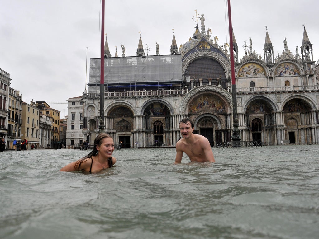 A young man and a woman enjoy swimming in flooded St. Mark's Square in Venice, Italy, Sunday, Nov. 11, 2012.