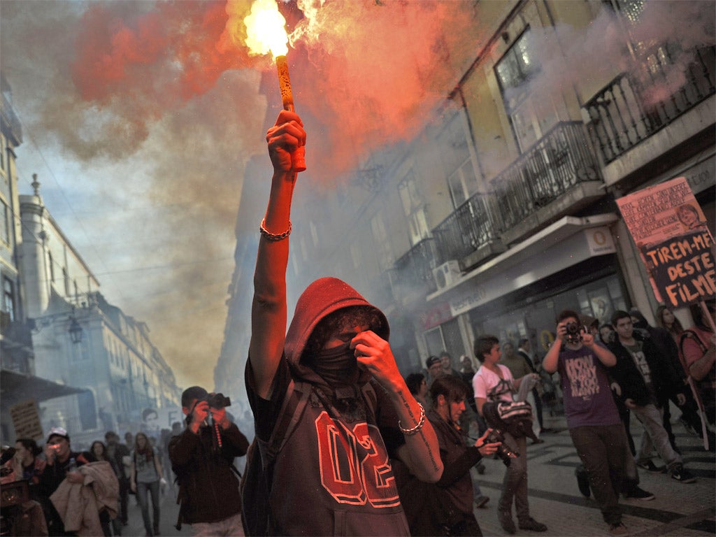 A protester holds a flare during a demonstration in Lisbon