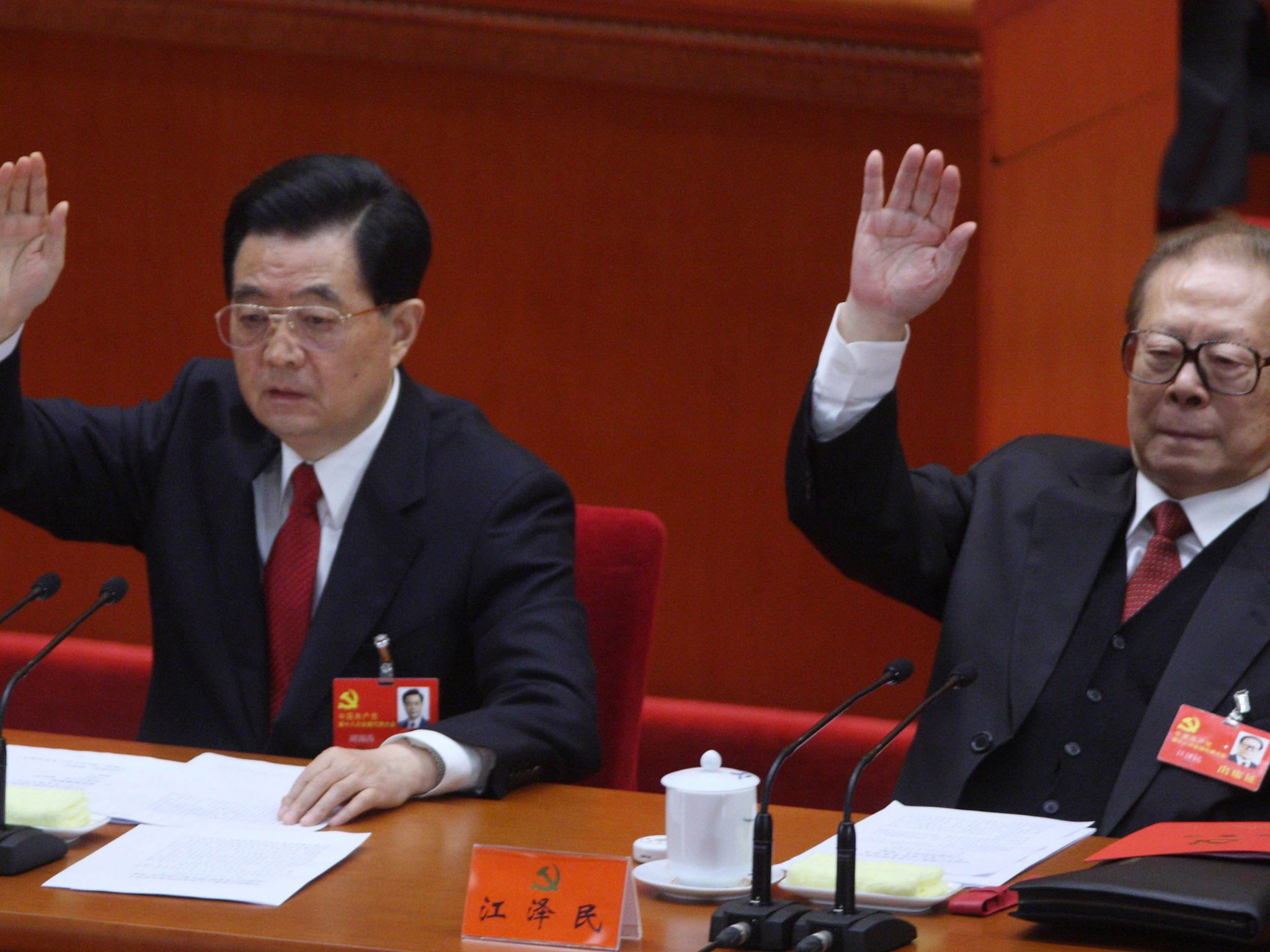 Hu Jintao, China's president, left, and Jiang Zemin, former president, raise their hands during the closing session of the 18th National Congress of the Communist Party of China