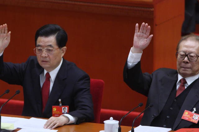 Hu Jintao, China's president, left, and Jiang Zemin, former president, raise their hands during the closing session of the 18th National Congress of the Communist Party of China