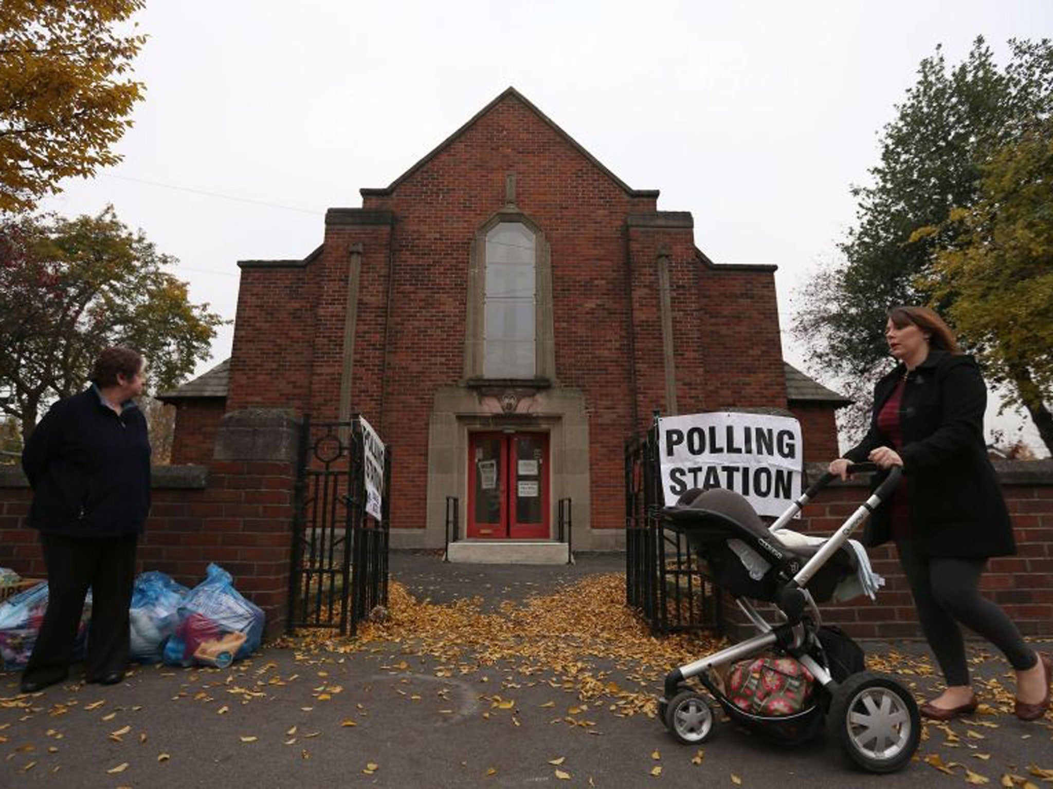 A woman pushes a pushchair past Davenport Methodist Church Polling Station in Stockport as voters go to the polls today to choose England and Wales's first police and crime commissioners