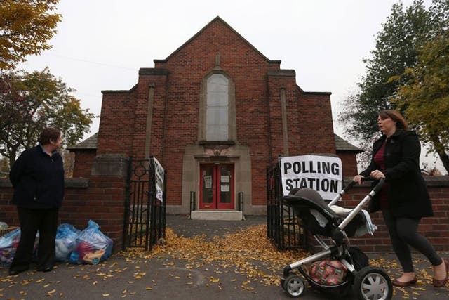 A woman pushes a pushchair past Davenport Methodist Church Polling Station in Stockport as voters go to the polls today to choose England and Wales's first police and crime commissioners