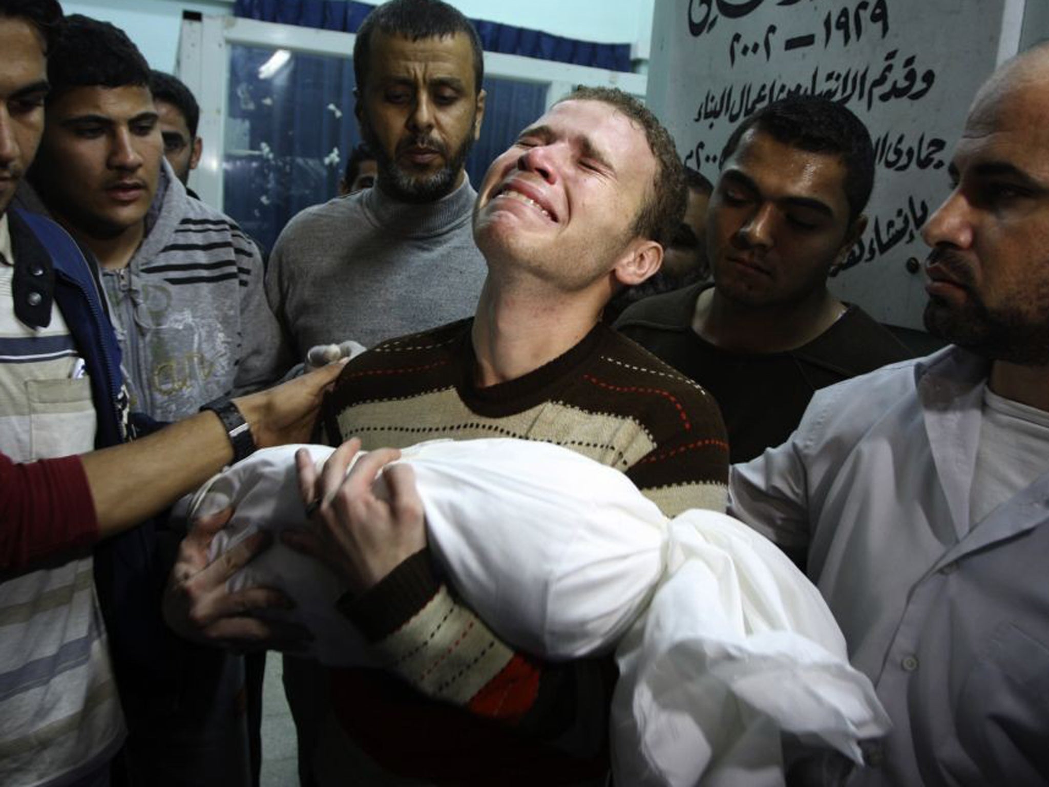 Jihad Misharawi weeps as he holds the body of his 11-month-old son Omar following an Israeli air strike in Gaza City