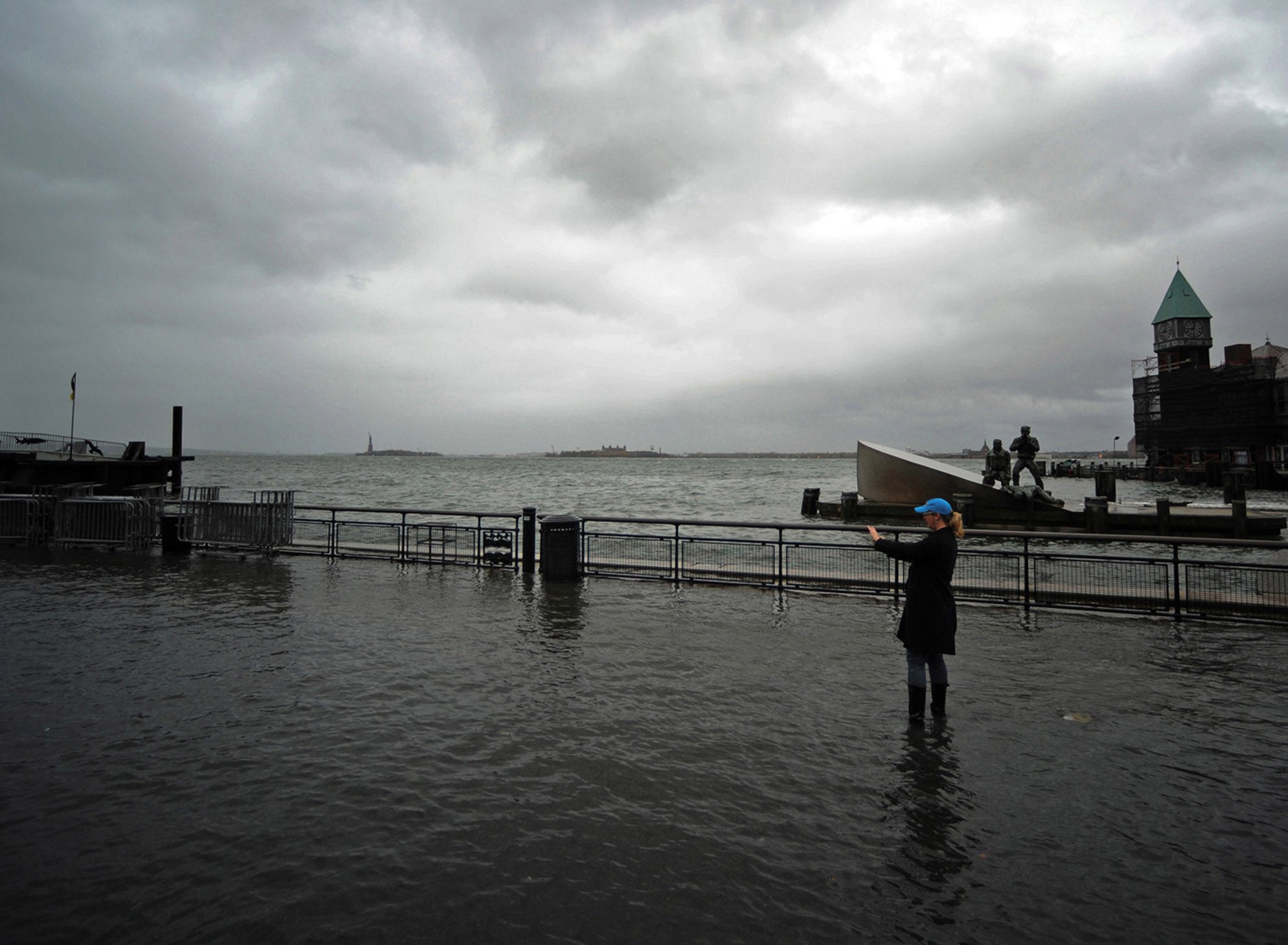 STORM DIKES: A woman takes a picture of a flooded area of Battery Park in New York on Oct. 29. With most scientists suggesting climate change is increasing the frequency of devastating storms, the cost-benefit ratio of building a surge-protection system m