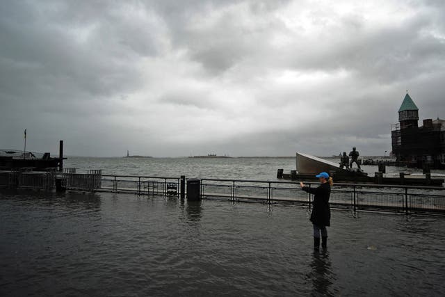 STORM DIKES: A woman takes a picture of a flooded area of Battery Park in New York on Oct. 29. With most scientists suggesting climate change is increasing the frequency of devastating storms, the cost-benefit ratio of building a surge-protection system m