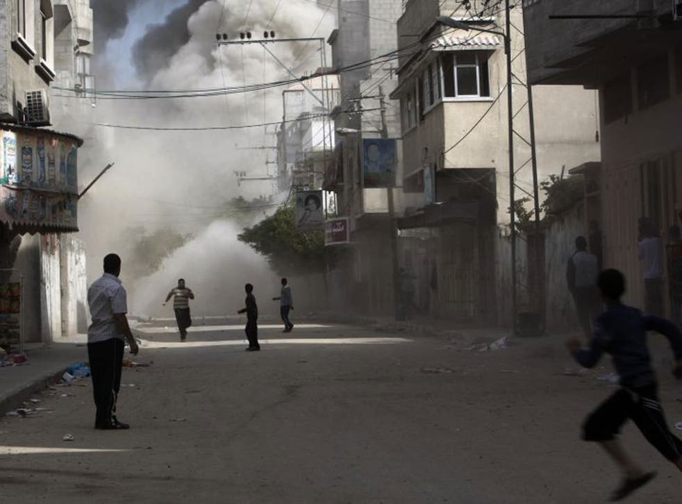 Palestinians run to take cover during an Israeli air strike on building in Gaza City