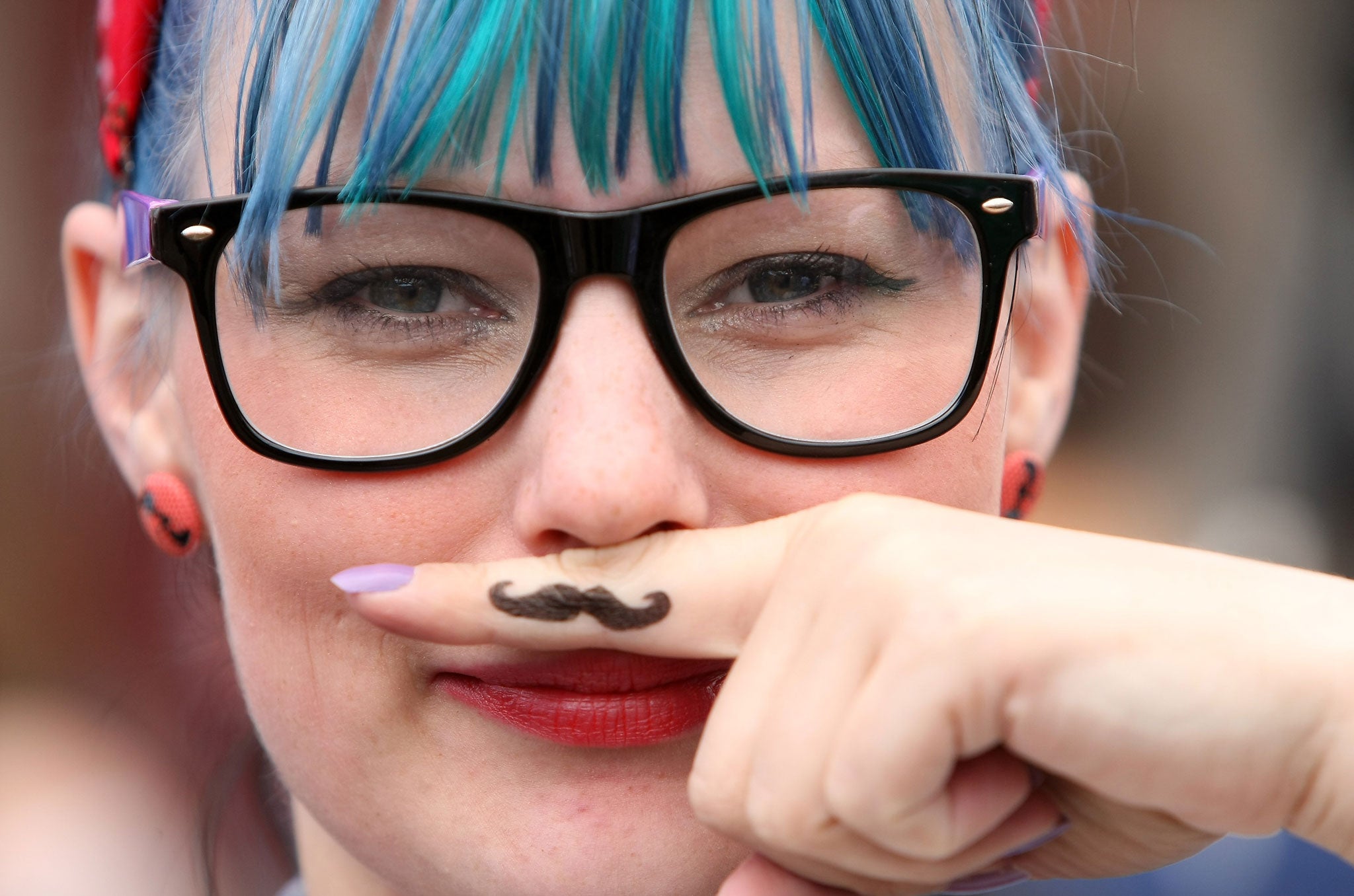 A visitor uses her finger as an ironic Hipster moustache at the second annual Hipster Olympics on July 21, 2012 in Berlin, Germany.