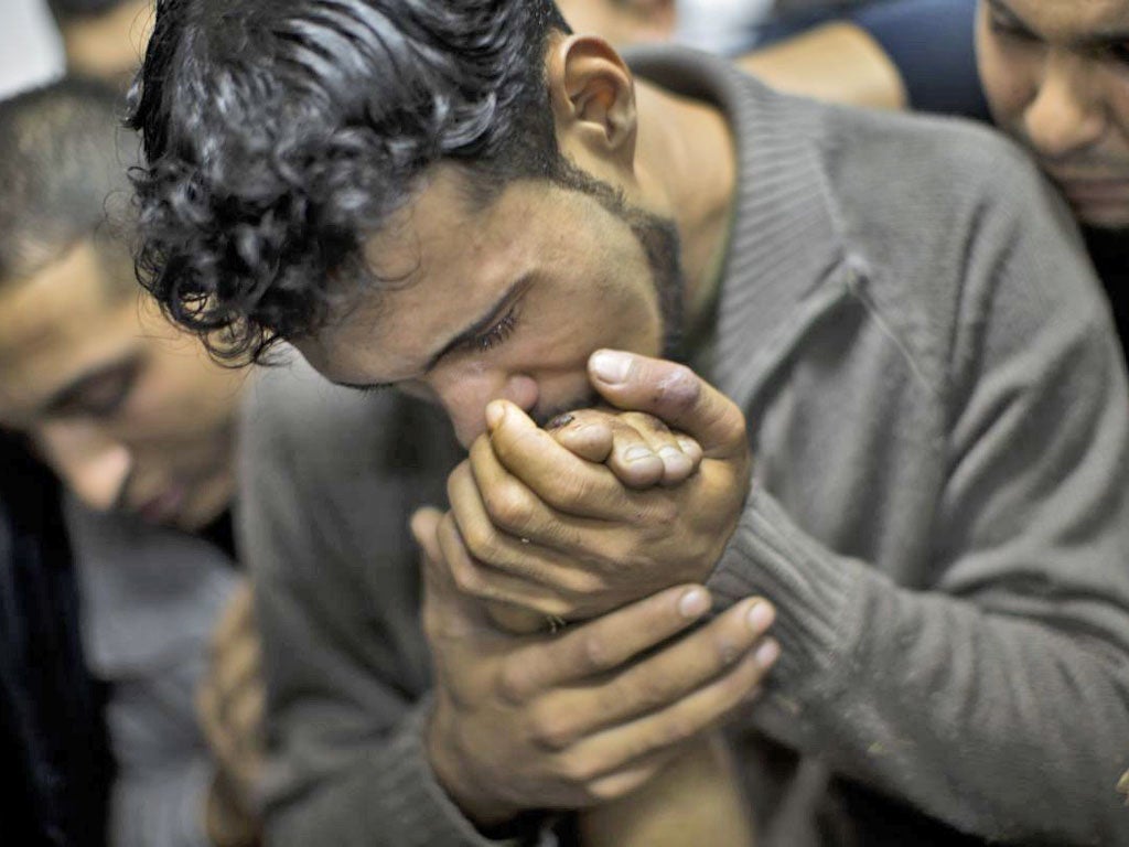 A Palestinian man kisses the hand of a dead relative in the morgue of Shifa Hospital in Gaza City