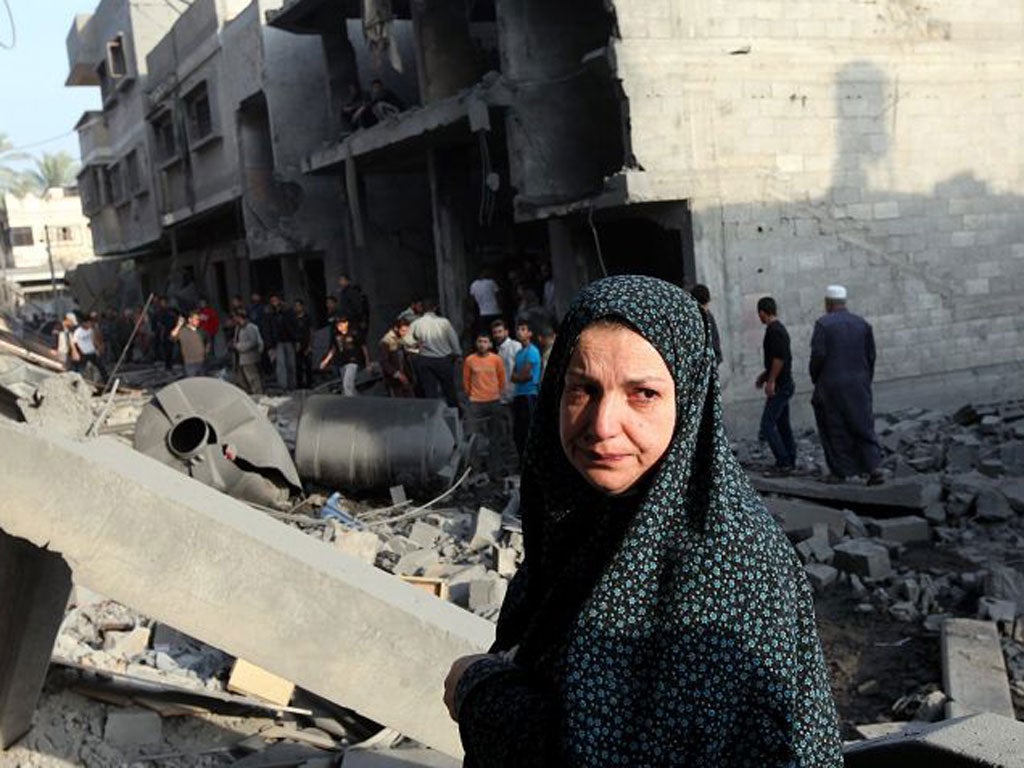 v2-A Palestinian woman inspects the rubble of her destroyed house after an Israeli air strike in the east of Gaza city
