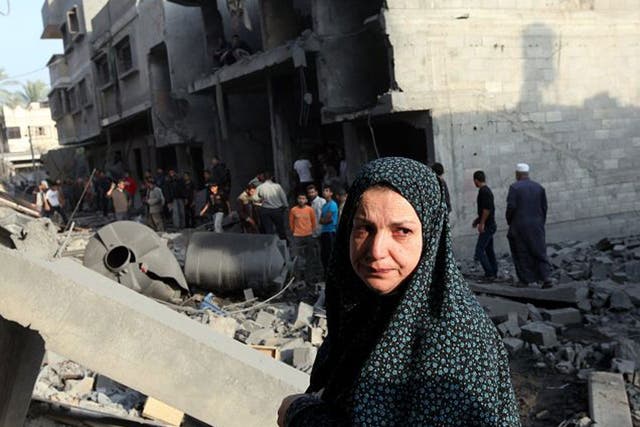 v2-A Palestinian woman inspects the rubble of her destroyed house after an Israeli air strike in the east of Gaza city