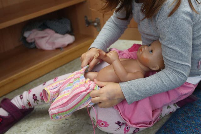 A girl gets a baby doll dressed up at a day care center for children aged 12 months to six years on December 22, 2011 in Munich, Germany