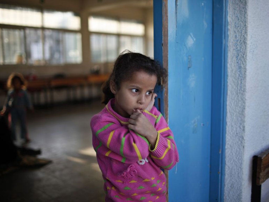 A displaced Palestinian girl, who fled her family's house, stands outside a classroom as she stays at a United Nations-run school in Gaza City
