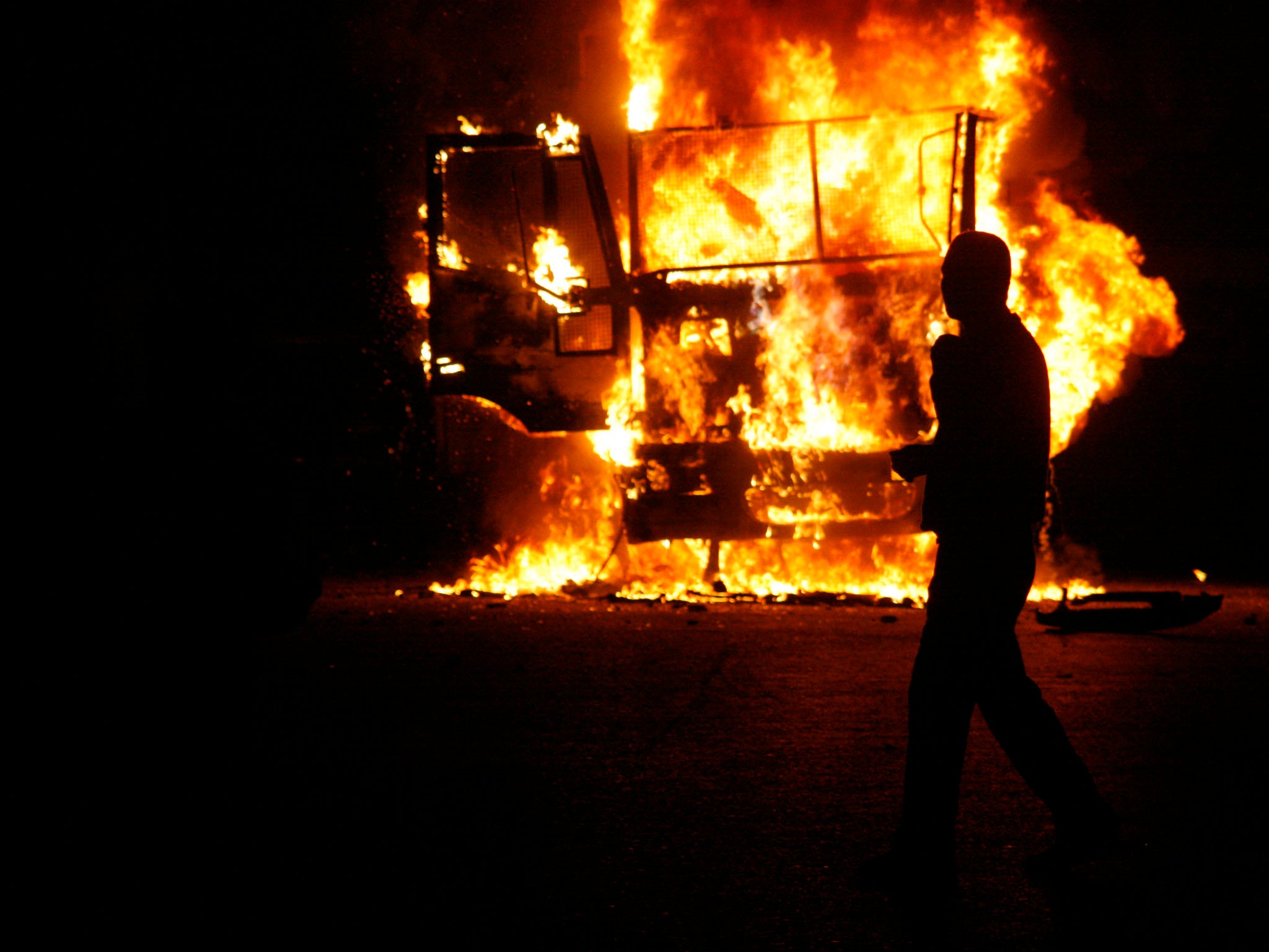An Egyptian man walks by a burning Egyptian police truck during a demonstration against Egypt's Islamist President Mohamed Morsi on November 23, 2012 in Cairo. Morsi insisted that Egypt is on the path to 'freedom and democracy' after granting himself swee