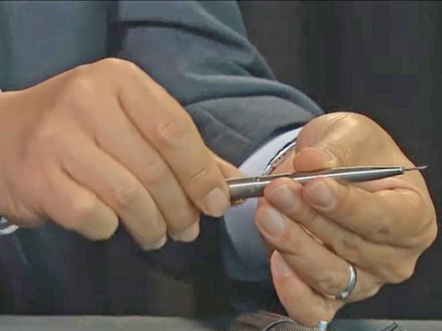 A South Korean investigator shows off the killer pen with its protruding poisoned needle