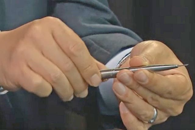 A South Korean investigator shows off the killer pen with its protruding poisoned needle