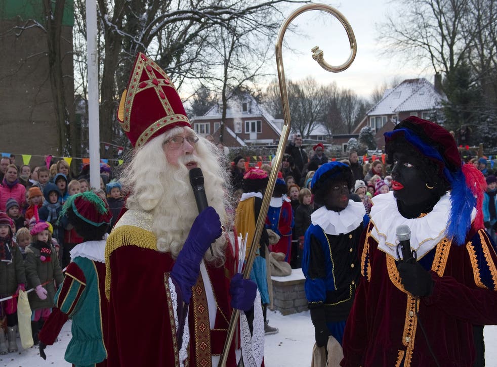 A man dressed as Saint Nicholas (or Sinterklaas) talks next to his Black Peters (or Zwarte Peter) during a celebration in a primary school, on December 3, 2010 in Soest, Netherlands.