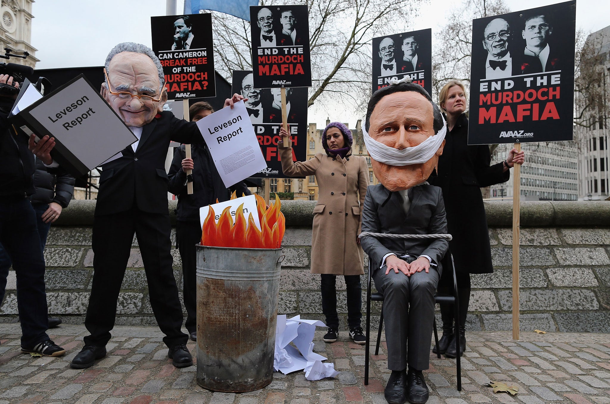 Protestors wear papier mache heads in the likeness of Rupert Murdoch and Prime Minister David Cameron outside the Queen Elizabeth II centre on November 29, 2012 in London, England.