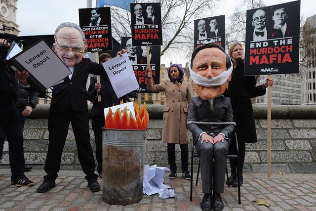 Protestors wear papier mache heads in the likeness of Rupert Murdoch and Prime Minister David Cameron outside the Queen Elizabeth II centre on November 29, 2012 in London, England.