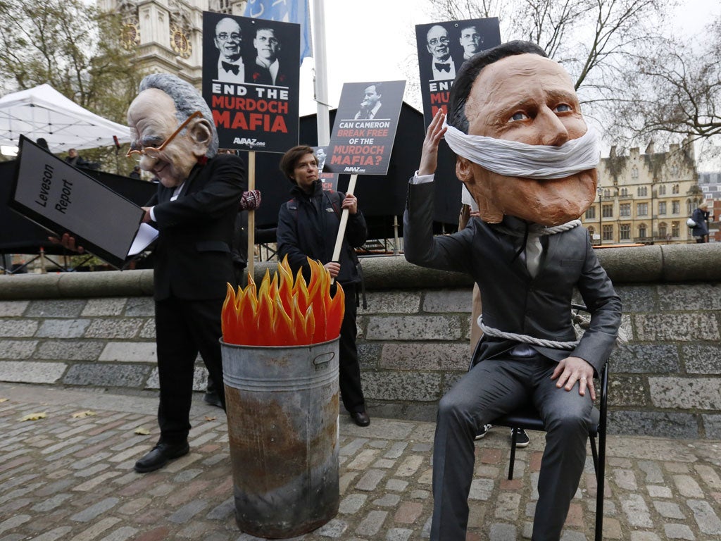 Burning issue: Protesters pose as Rupert Murdoch and David Cameron as the Leveson report comes out