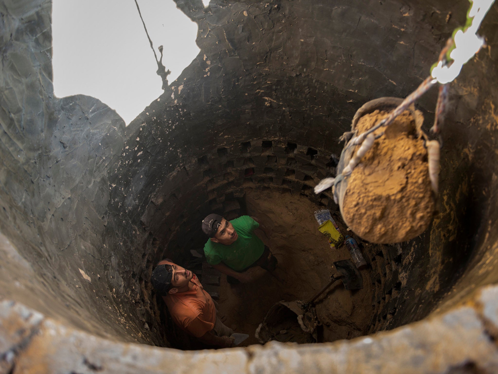 MIDEAST TUNNELS: Ismael al-Arja, 25, and Mahmoud al-Arja, 25, watch as a bucket of soil is hoisted out of the tunnel they are digging along the Egypt-Gaza border.