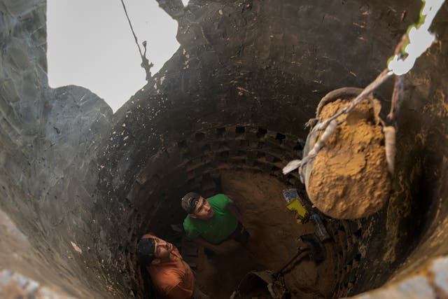MIDEAST TUNNELS: Ismael al-Arja, 25, and Mahmoud al-Arja, 25, watch as a bucket of soil is hoisted out of the tunnel they are digging along the Egypt-Gaza border.  
