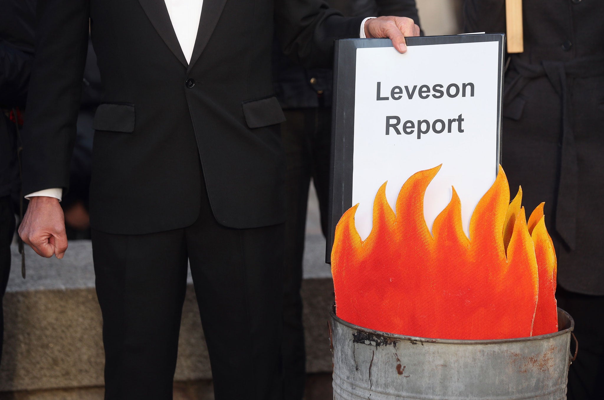A protest group campaigning against the political dominance of Rupert Murdoch stage a mock burning of a copy of the Leveson Report outside the Queen Elizabeth II centre on November 29, 2012 in London, England.