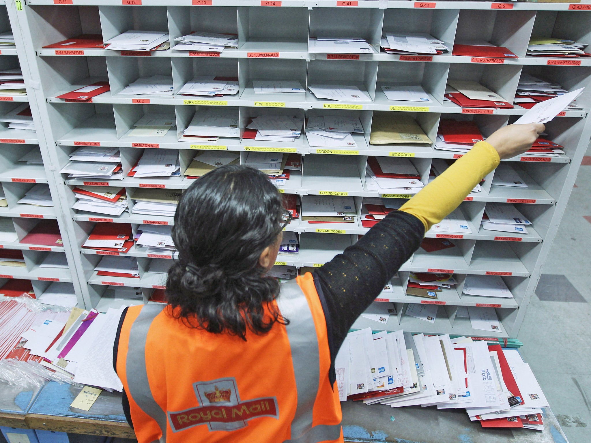 A Royal Mail worker handles mail at a sorting office