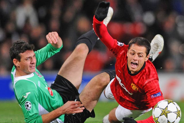 Manchester United’s Javier Hernandez falls under a challenge from Cluj’s Ionut Rada