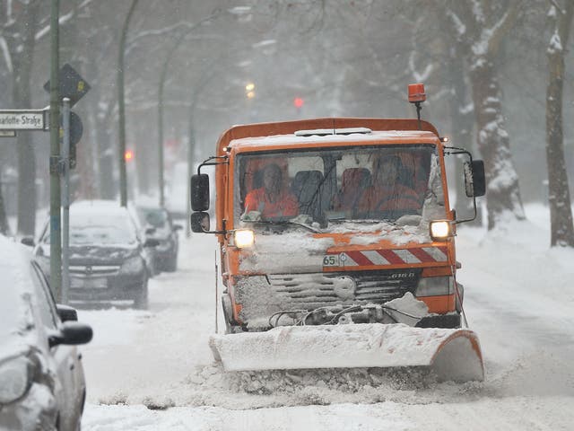 A snow plough makes its way through an East German street