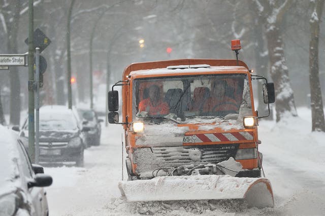 A snow plough makes its way through an East German street
