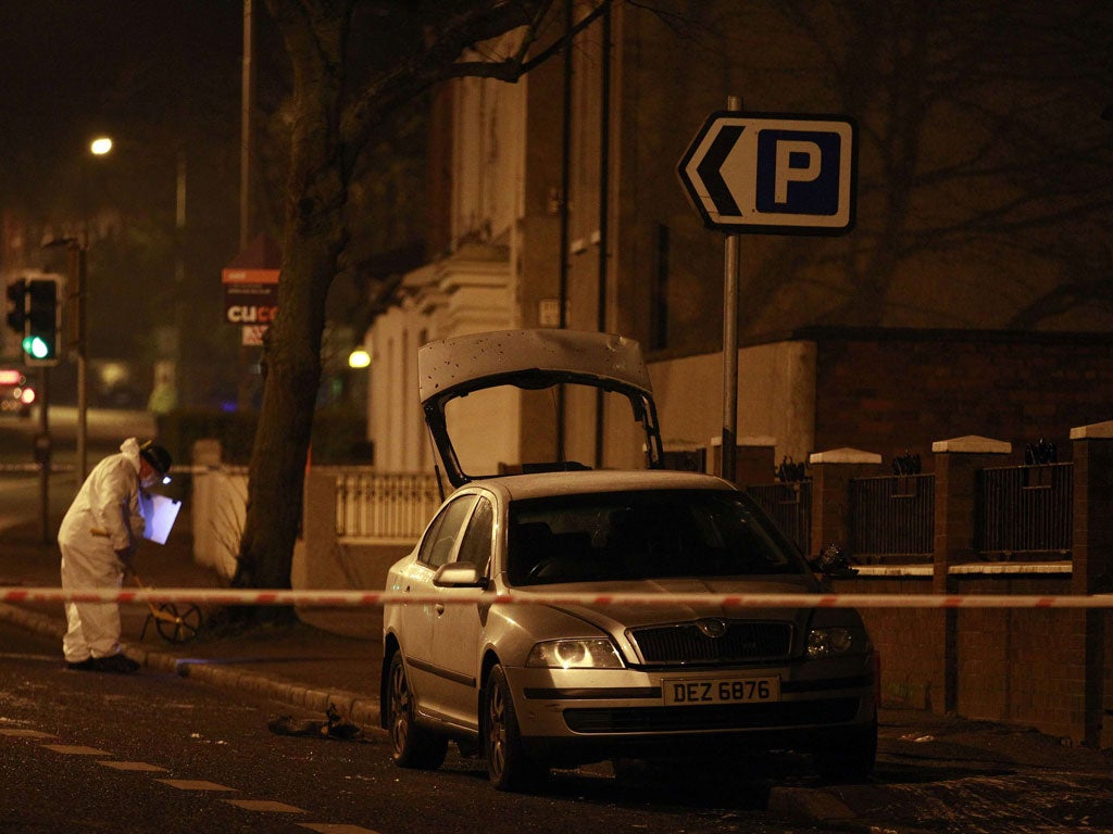 A forensic officer works around a burnt out unmarked police car in East Belfast