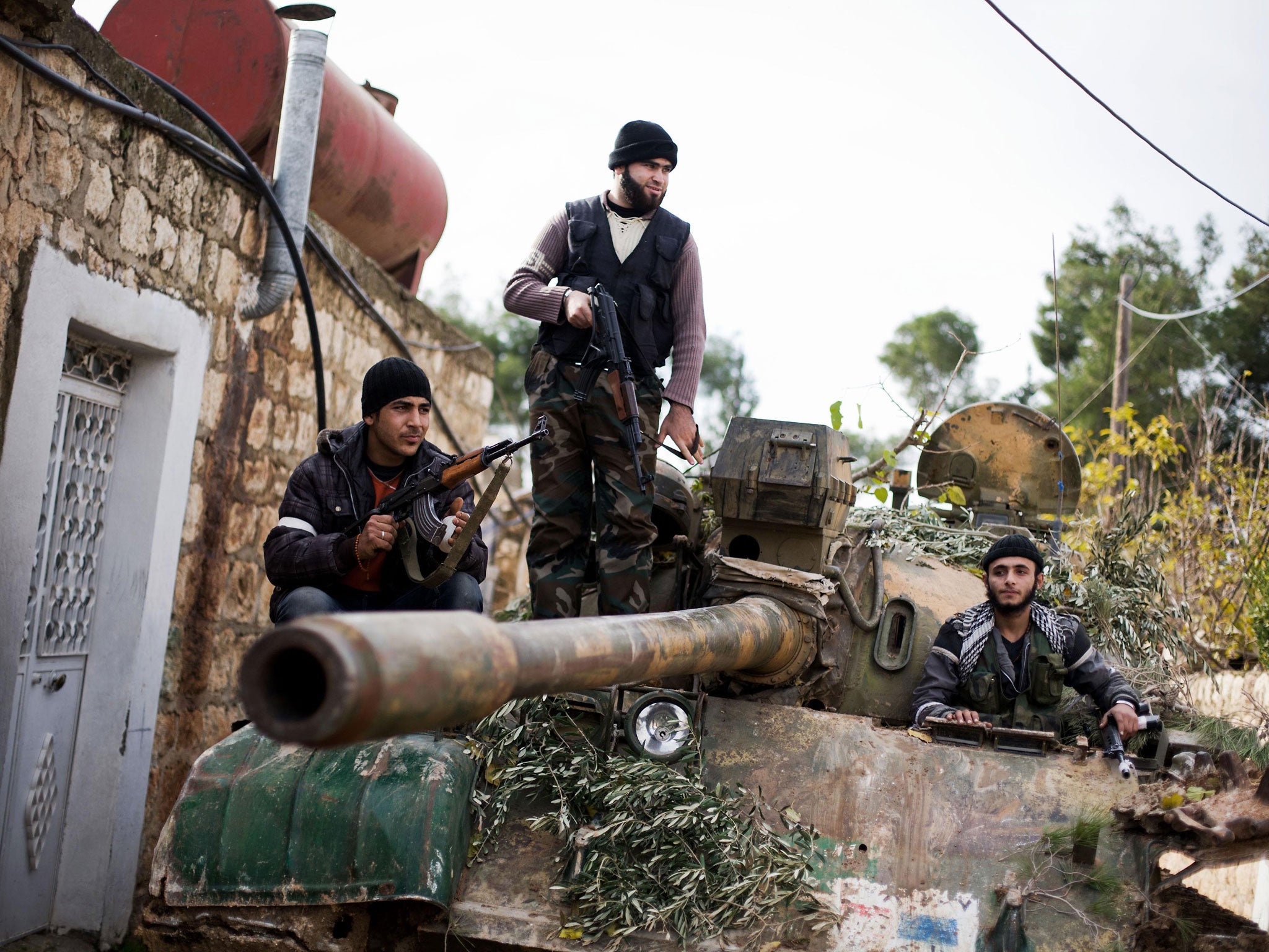 Kurdish members of the Free Syrian Army on a tank stolen from regime forces in the north of Aleppo province