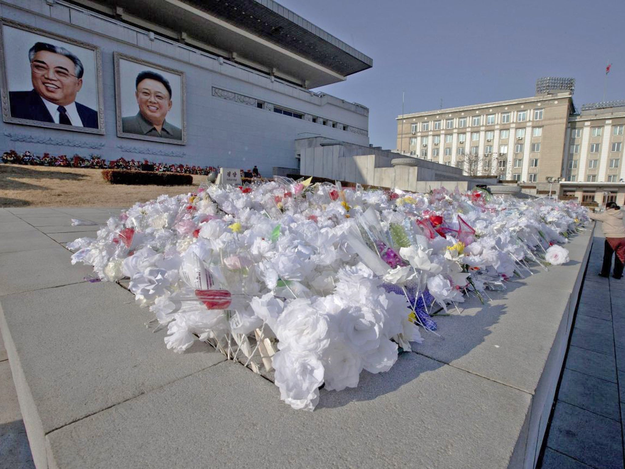 A North Korean woman and a child pay respect to portraits of the late leaders Kim Il Sung, left, and Kim Jong-il on Kim Il Sung Square in Pyongyang