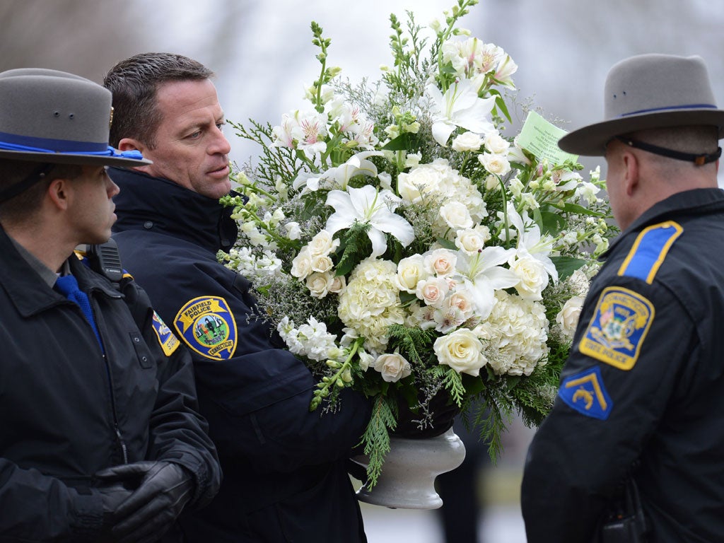 Police officers help move floral arrangements to following the funeral of Noah Pozner