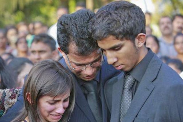 Jacintha Saldanha's widower Ben Barboza (centre) and her children Lisha (left) and Junal mourn during her funeral at a cemetery in Shirva
