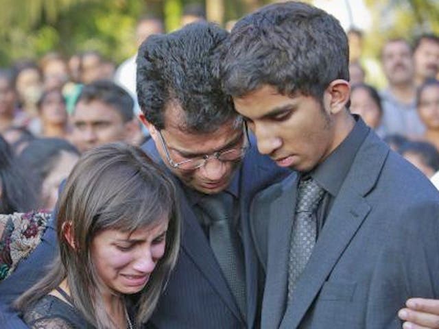 Jacintha Saldanha's widower Ben Barboza (centre) and her children Lisha (left) and Junal mourn during her funeral at a cemetery in Shirva